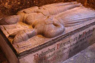 A stone monument to Lord Portlester and his third wife. There are depicted in peaceful repose, he with his sword and armour in the style of a Norman knight and baron, she with her splendid hat and long fluted dress. The soft compact shape lying at her feet is actually a small dog.
