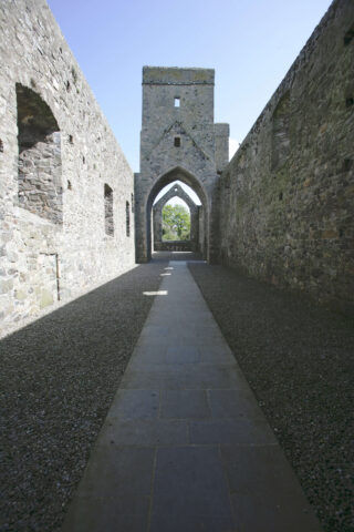 internal ruins of the abbey, with a tower up ahead and two archways one after the other