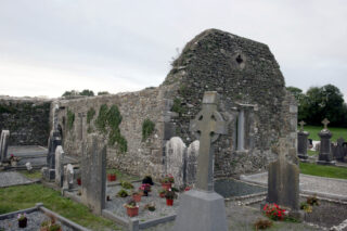 exterior view of the church ruins, with gravestones surrounding its outside.