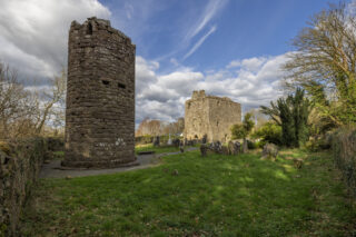 view of the round tower ruins and church within a grassy cemetery