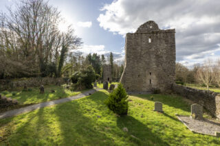 view of the church on a sunny day, as the sun shines through the tree branches.